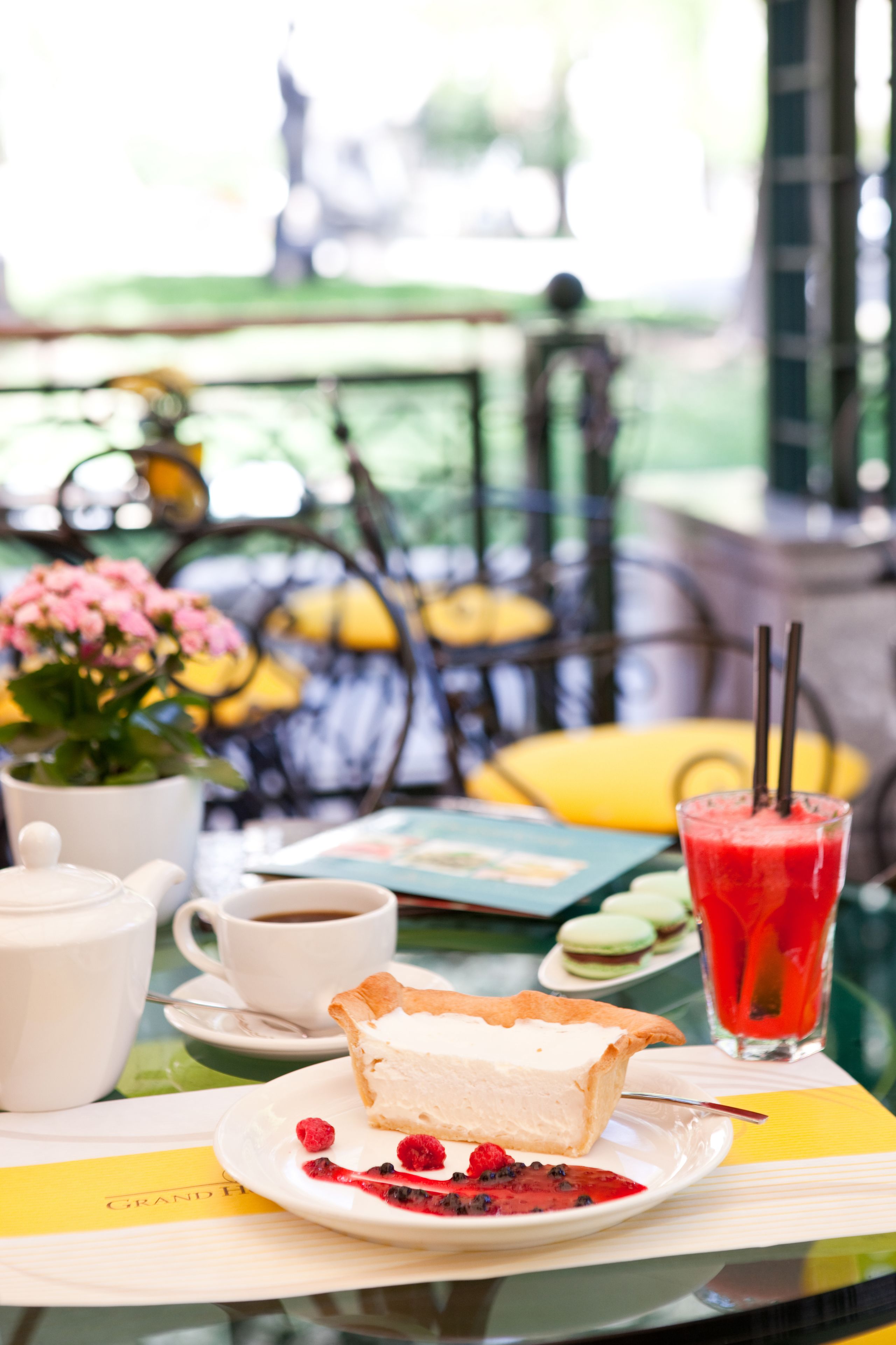A table with a dessert plate, a cup of coffee, a glass of red drink, and a teapot.