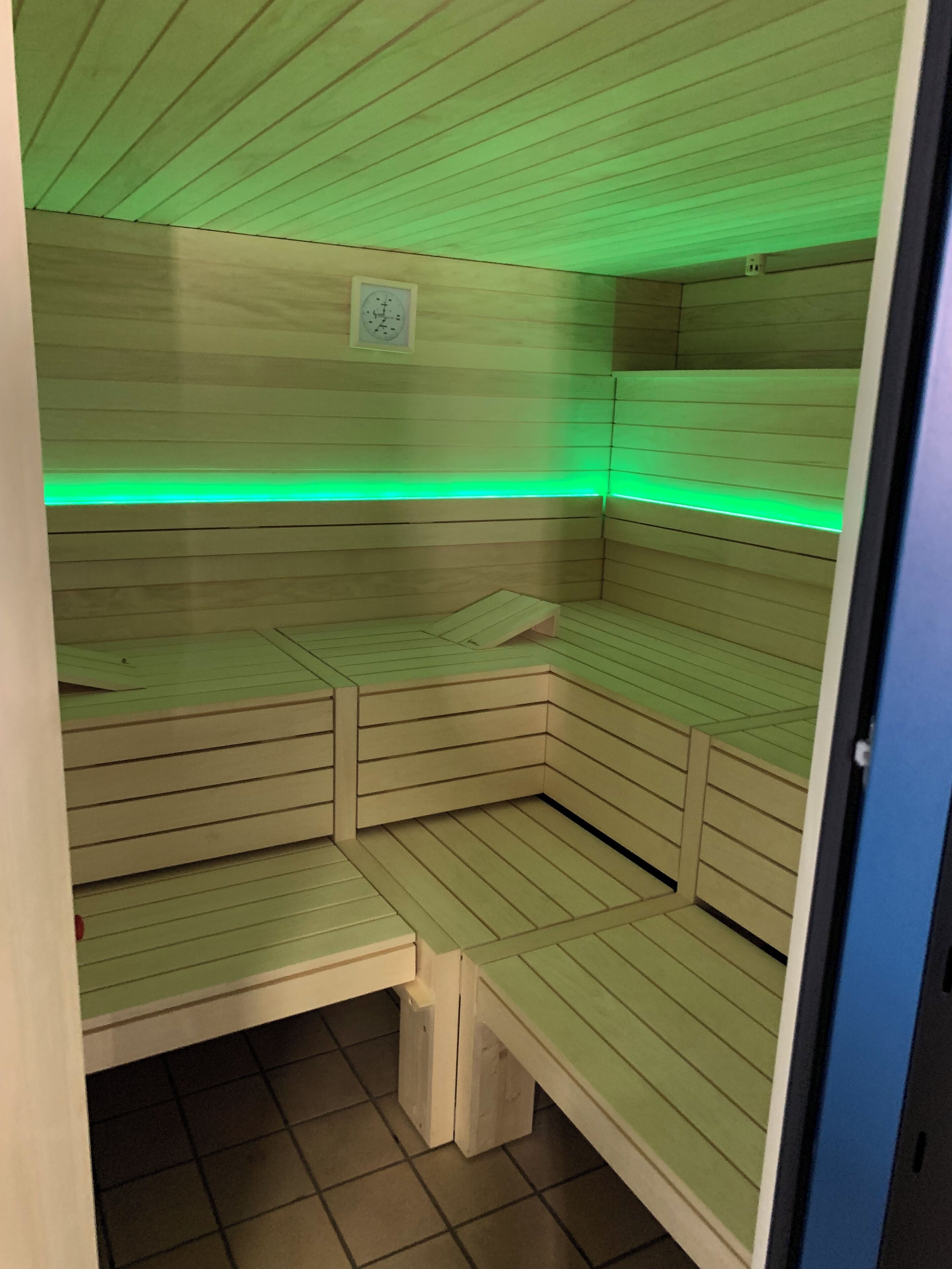 A sauna with wooden benches and a green light strip.