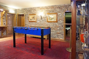 Relax in a spacious room with a foosball table and framed artwork, surrounded by comfortable seating areas.