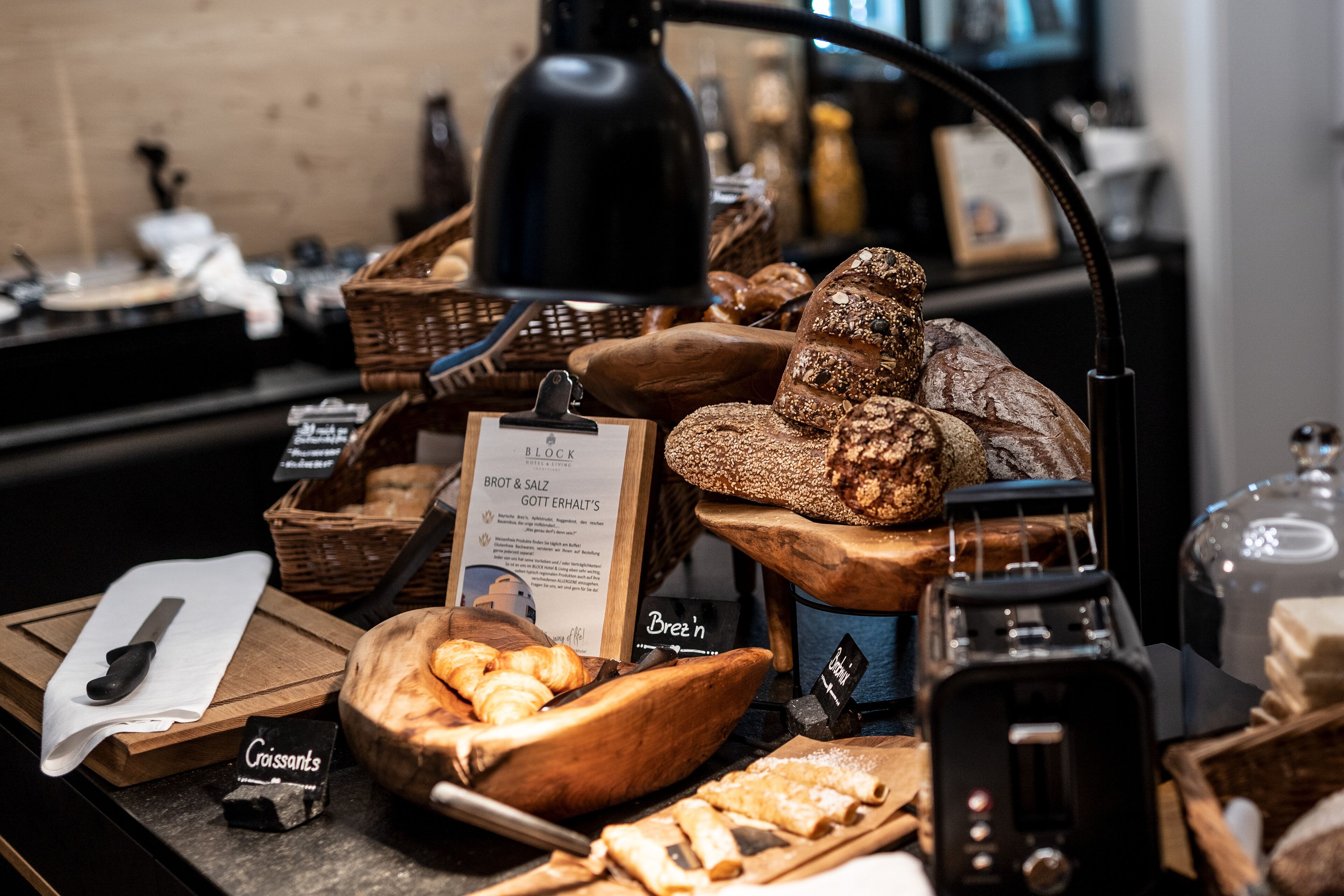 Eine Bäckerauslage mit verschiedenen Broten und Gebäck, ein Schild mit der Aufschrift Brot & Salz und ein Toaster.