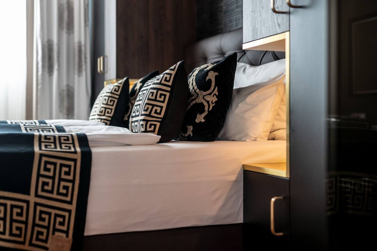 A neatly made bed with patterned pillows and a dark headboard.