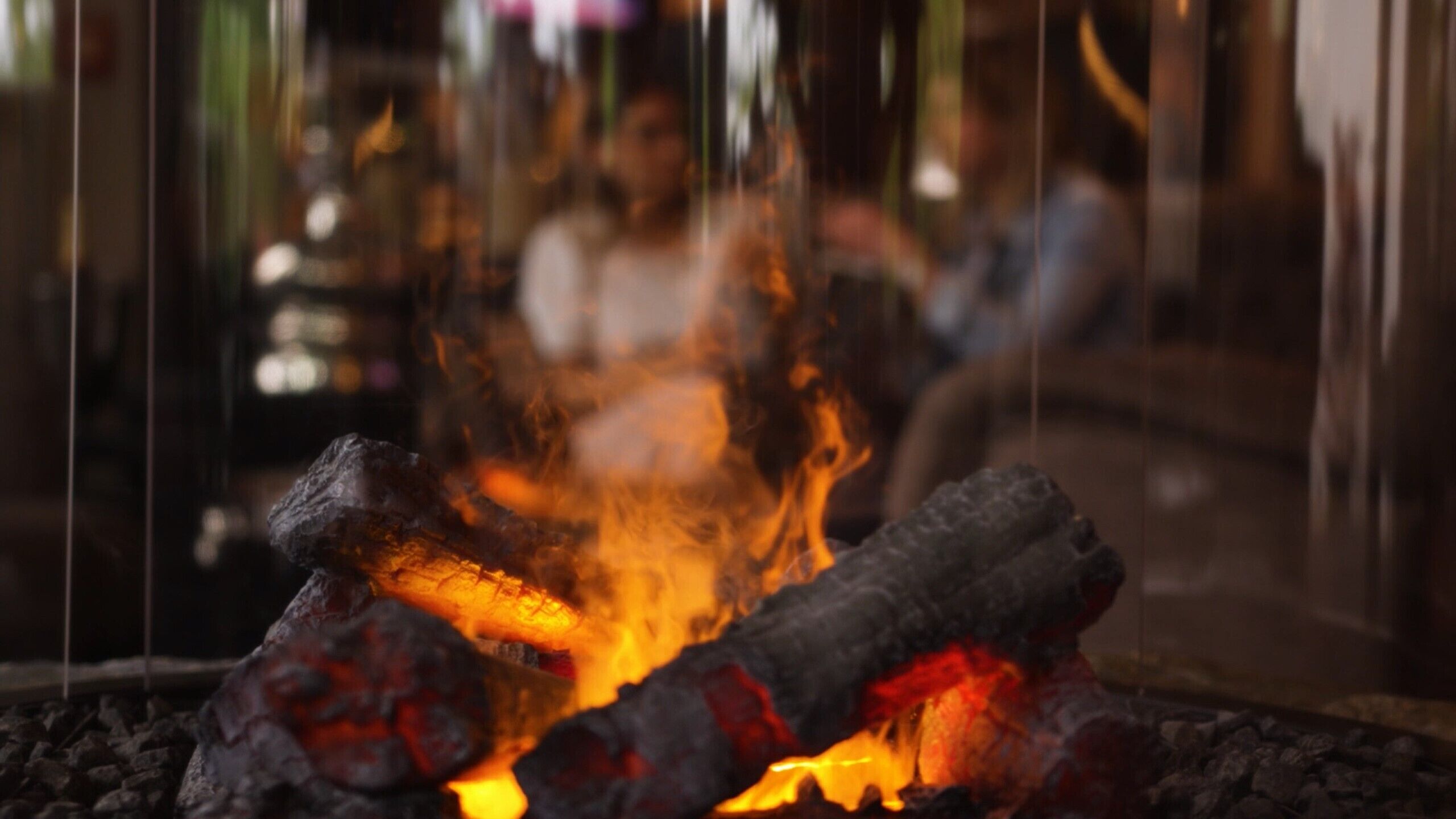 Primer plano de un fuego con leña ardiendo y brasas.