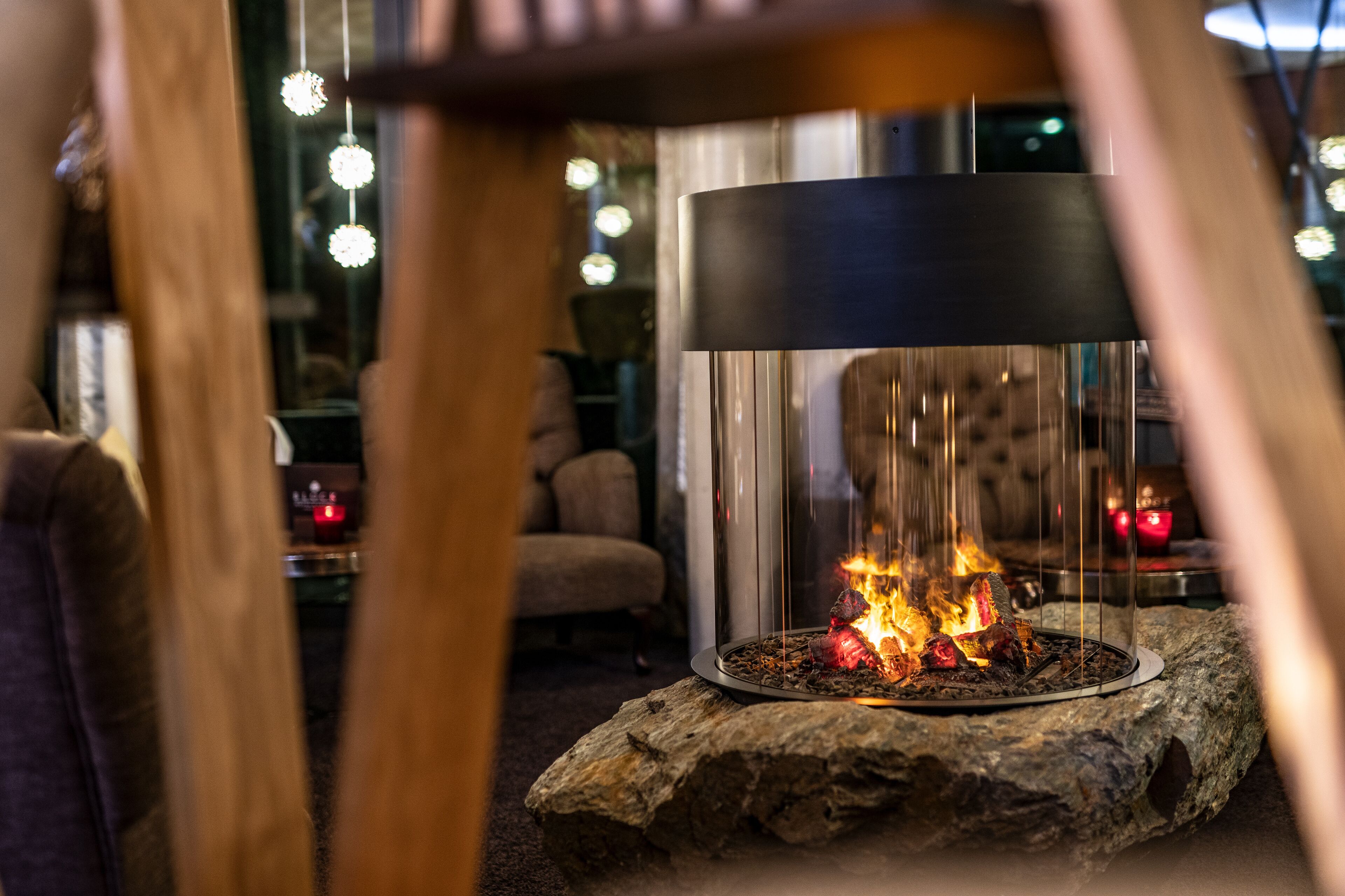 A cozy indoor setting with a central fire feature, a modern lamp, and ambient lighting.