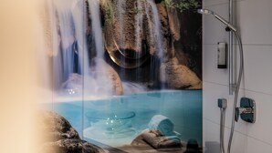 Un'area benessere con una cascata, una vasca in vetro e una doccia.