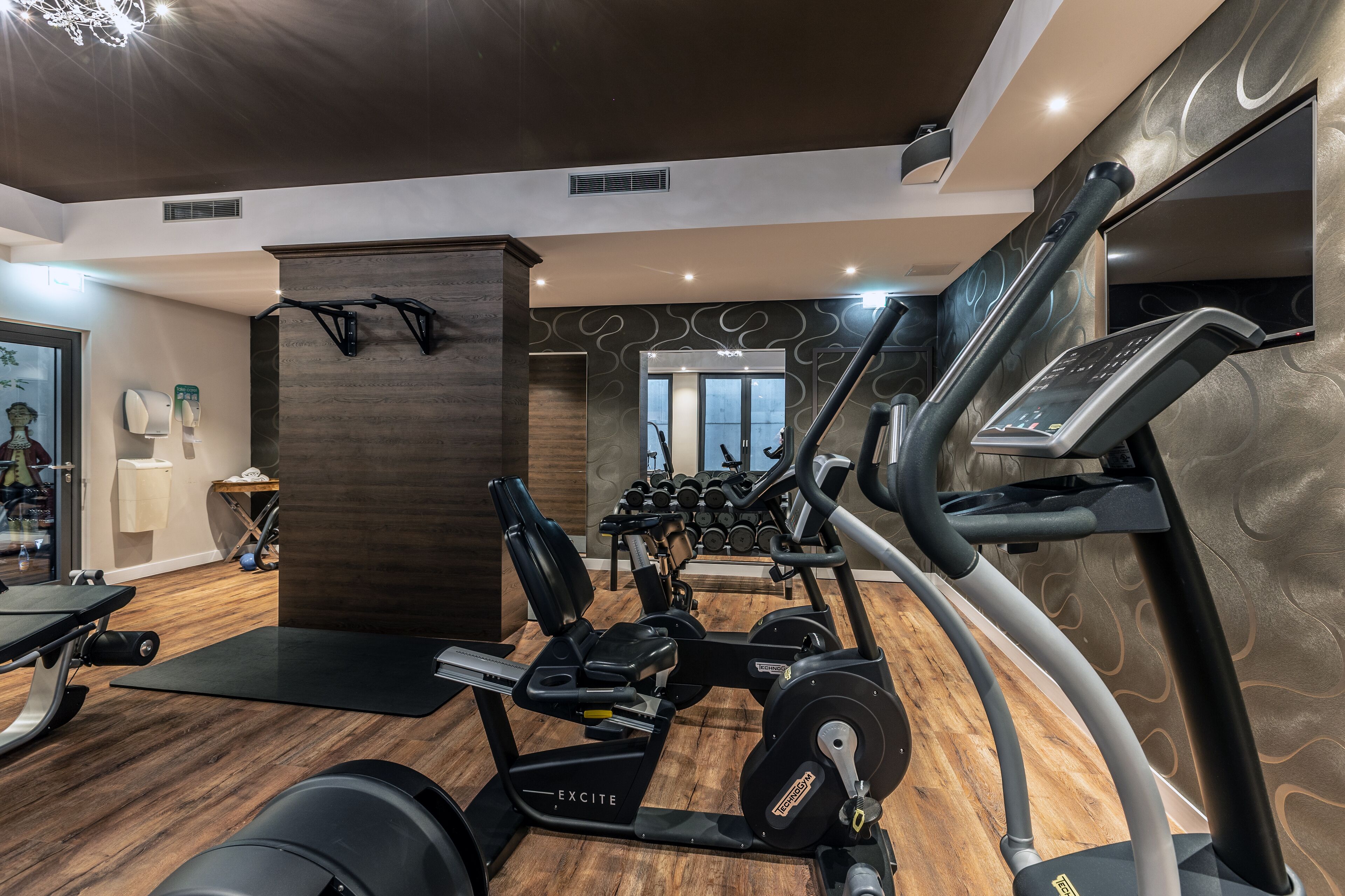 A gym with cardio machines, weight benches, and dumbbells.