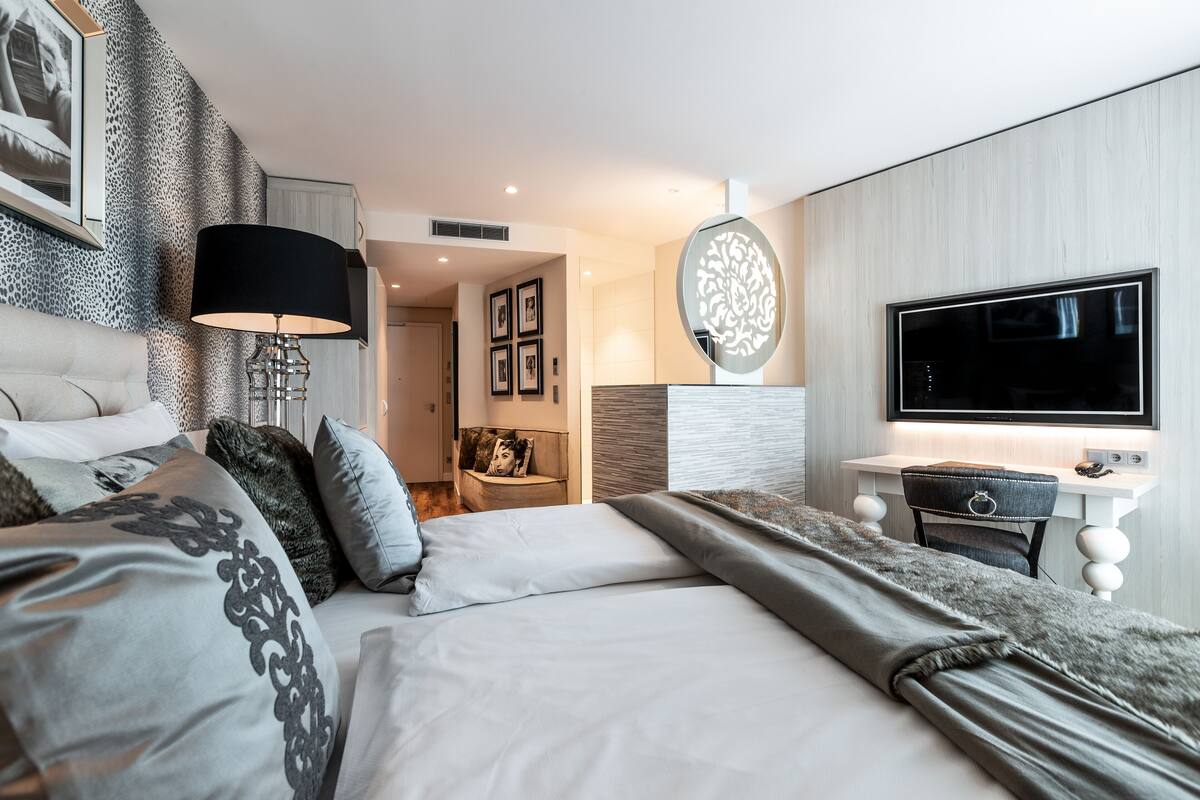 A modern hotel room with a large bed, a desk, and a TV.
