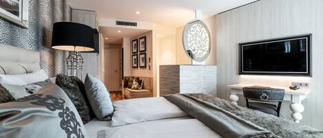 A modern hotel room with a large bed, a desk, and a TV.