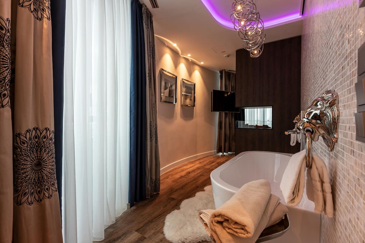 A modern bathroom with a freestanding bathtub, a fluffy white rug, and a wall-mounted towel rack.