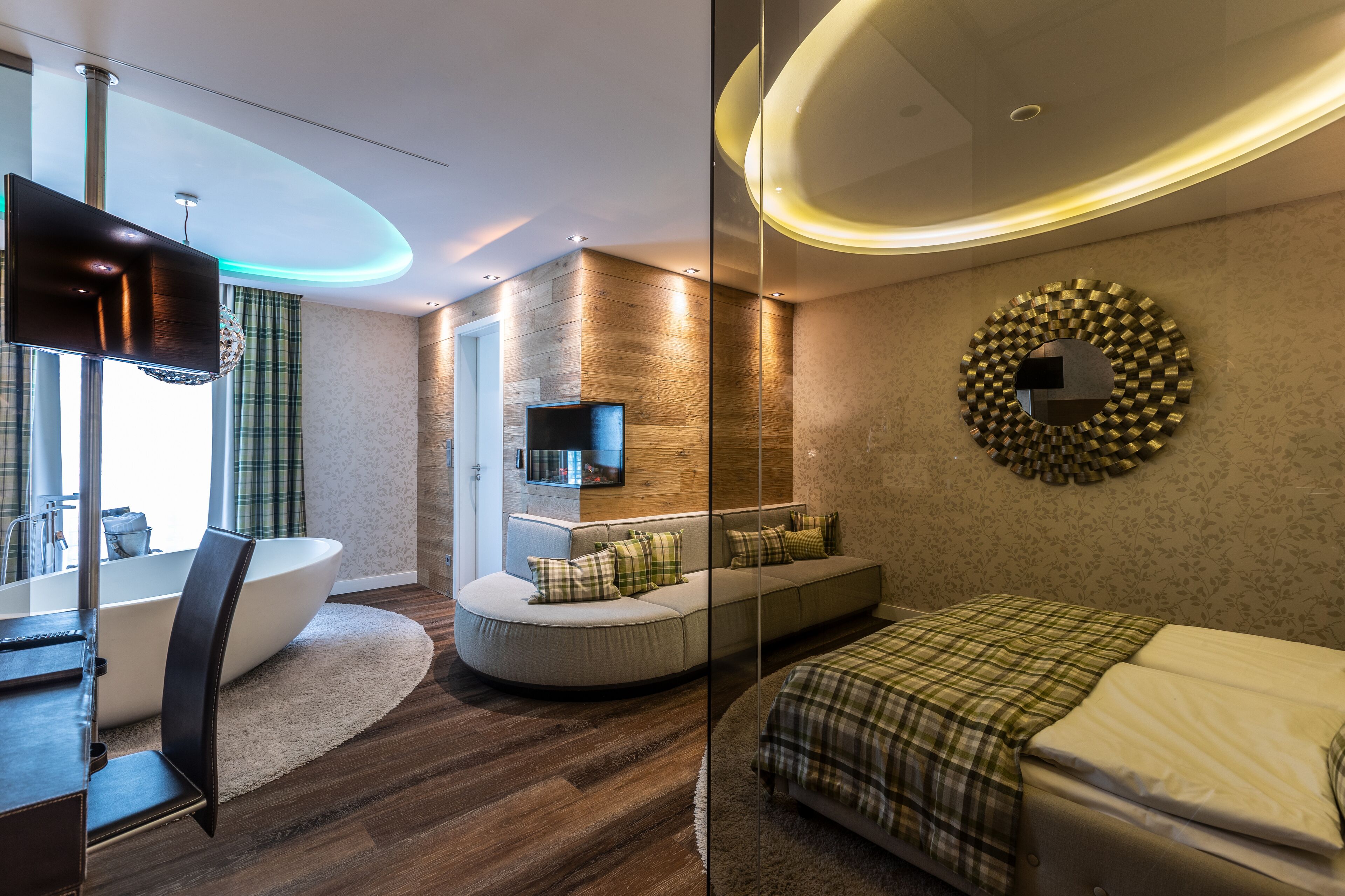 Une chambre d’hôtel moderne dotée d’une grande baignoire, d’un canapé, d’un lit et d’un téléviseur.