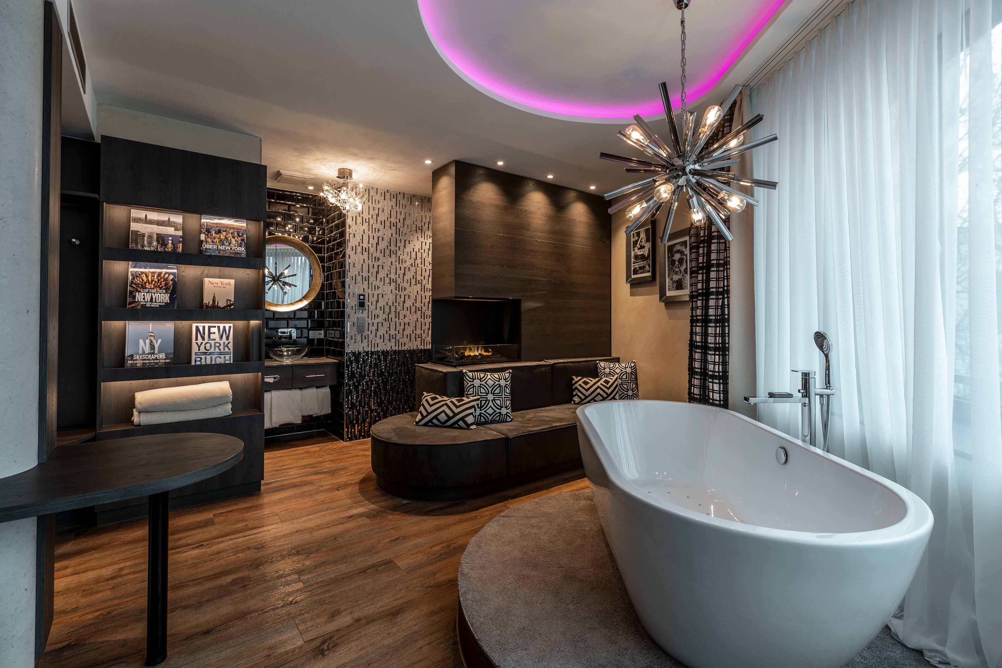 Een moderne badkamer met een vrijstaand bad, een wastafelmeubel en een zithoek met een televisie.