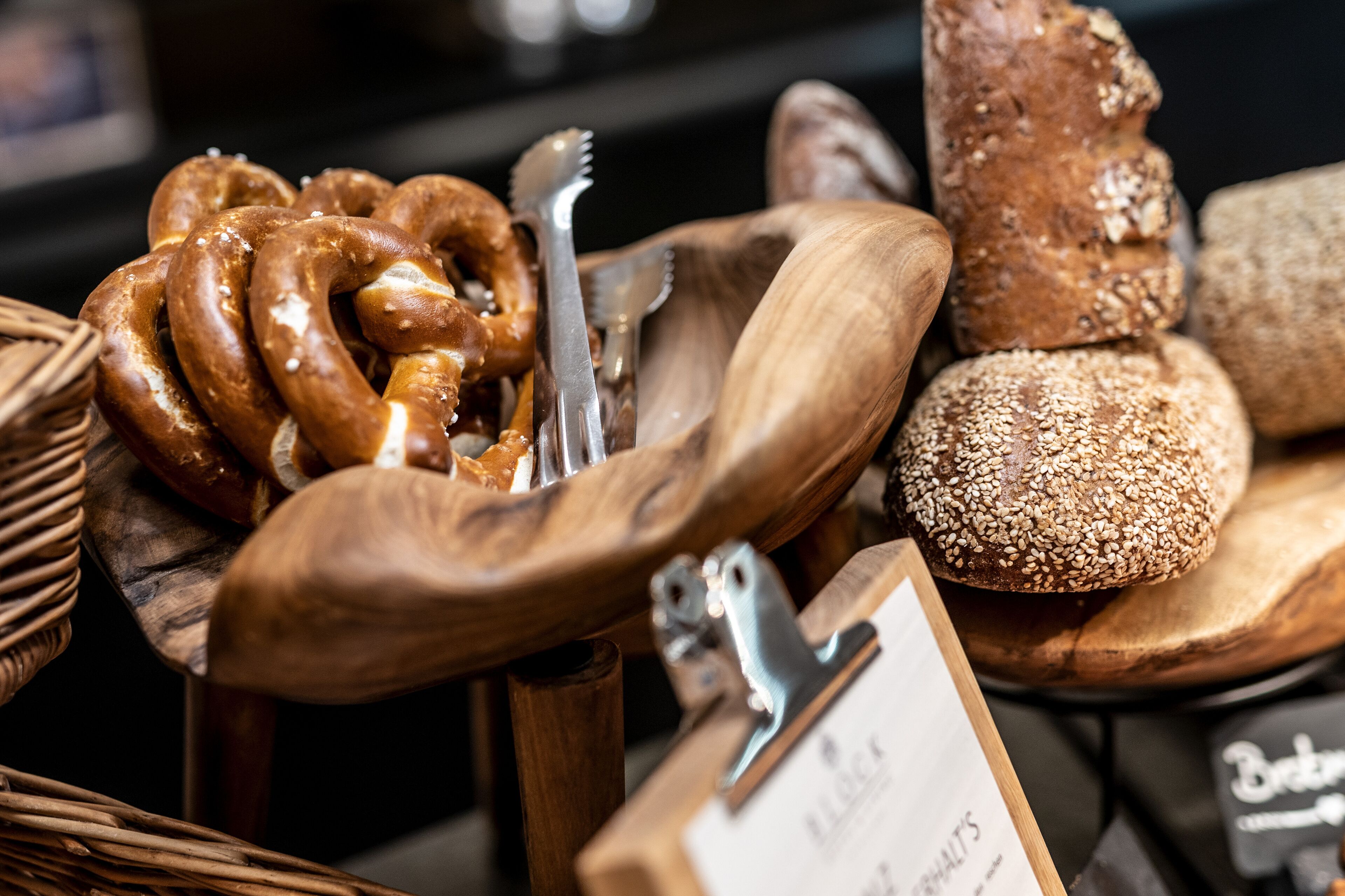 A variety of baked goods including pretzels, bread, and a wooden serving tray with utensils.