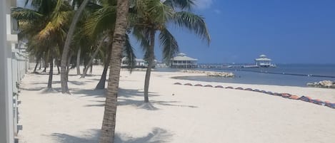 Na praia, areia branca, espreguiçadeiras, toalhas de praia 