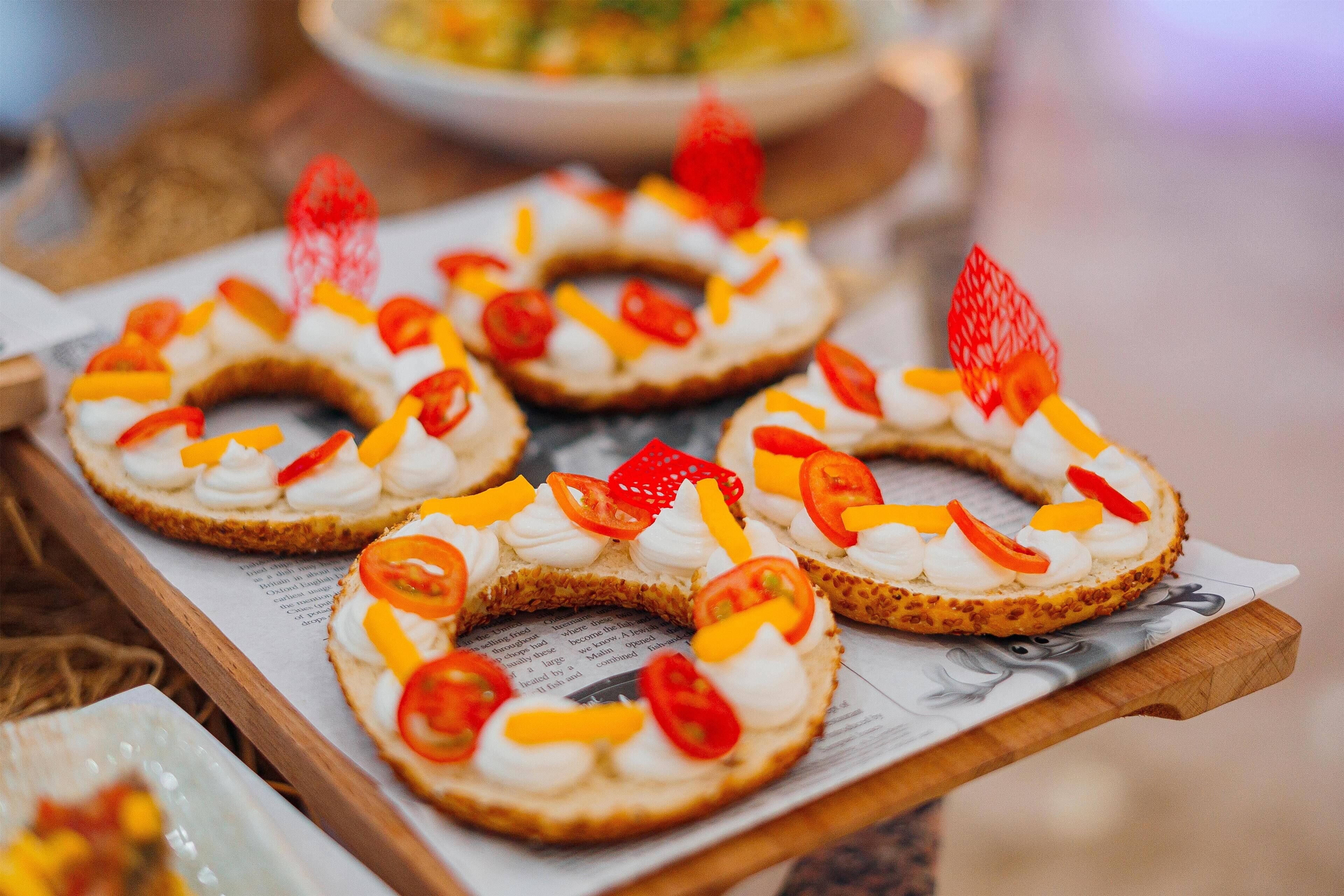 A tray of decorated bagels with cream cheese and sliced vegetables.