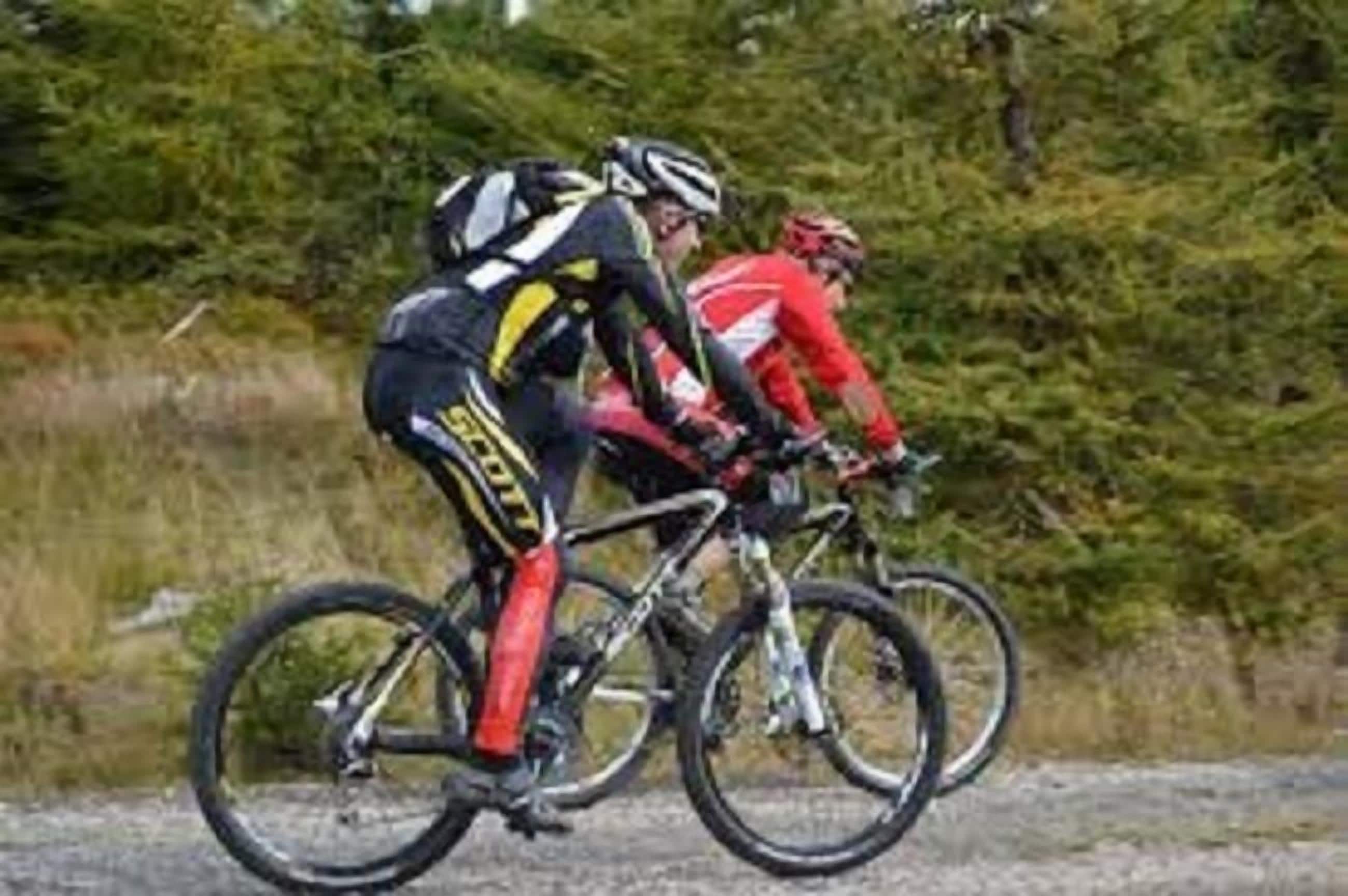 Two cyclists on a gravel path with dense greenery in the background.
