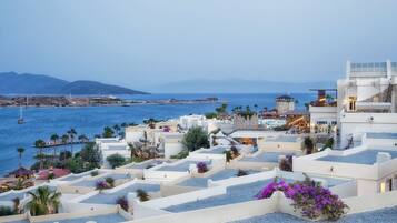 Un resort costero con edificios blancos, una zona de piscina y vistas al mar y a las montañas.