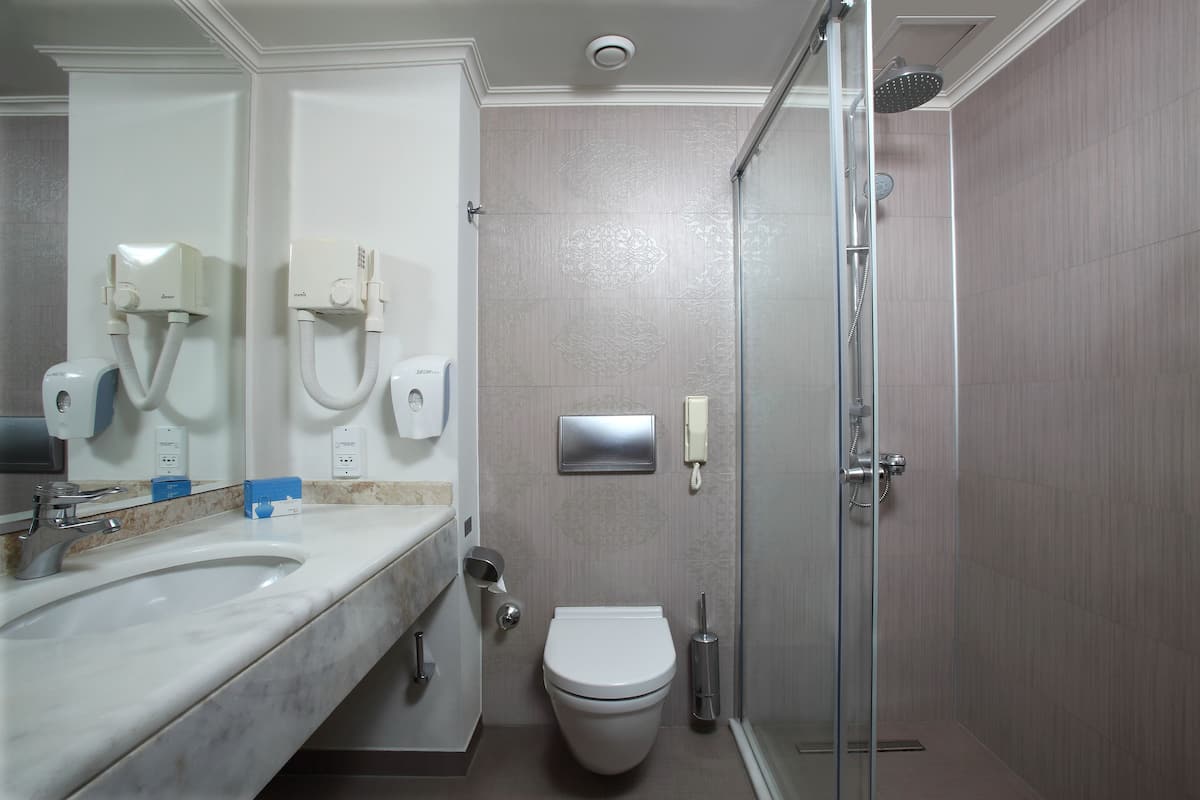 Une salle de bain moderne avec un lavabo en marbre, des toilettes et une douche à parois de verre.