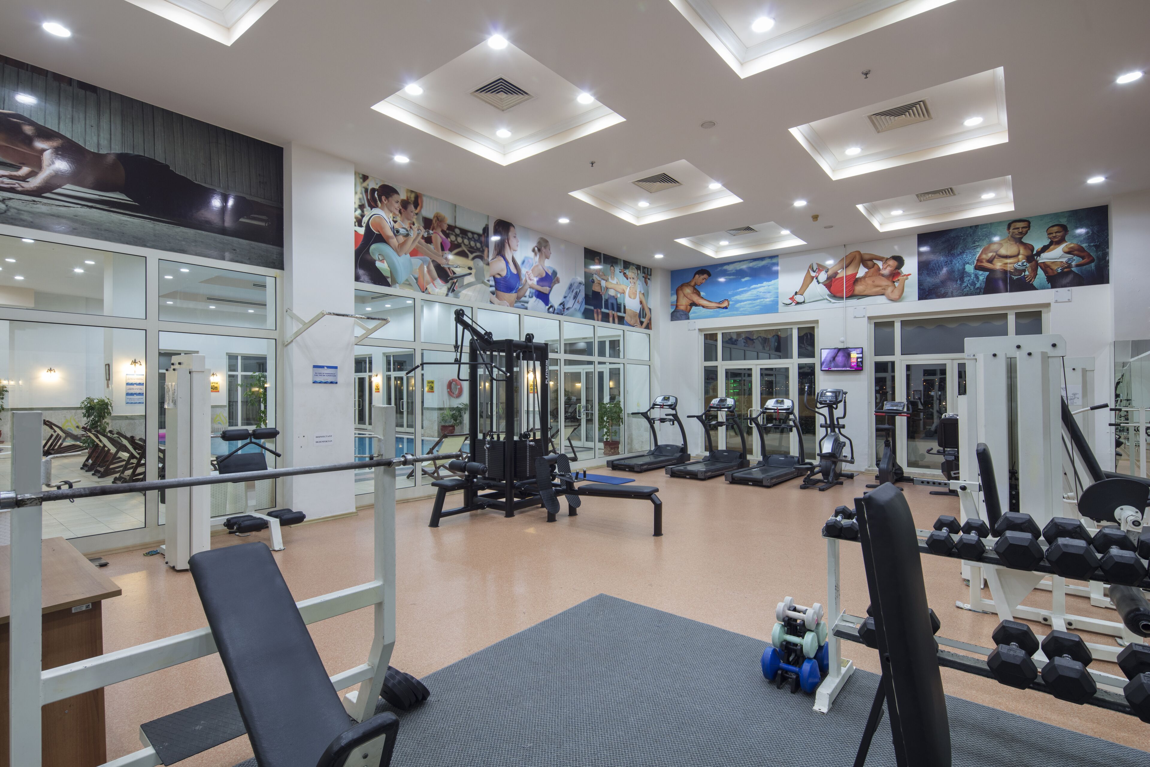 A gym with exercise equipment, mirrors, and motivational posters on the walls.
