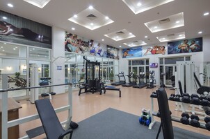 Un gimnasio con equipo de ejercicio, espejos y carteles motivacionales en las paredes.
