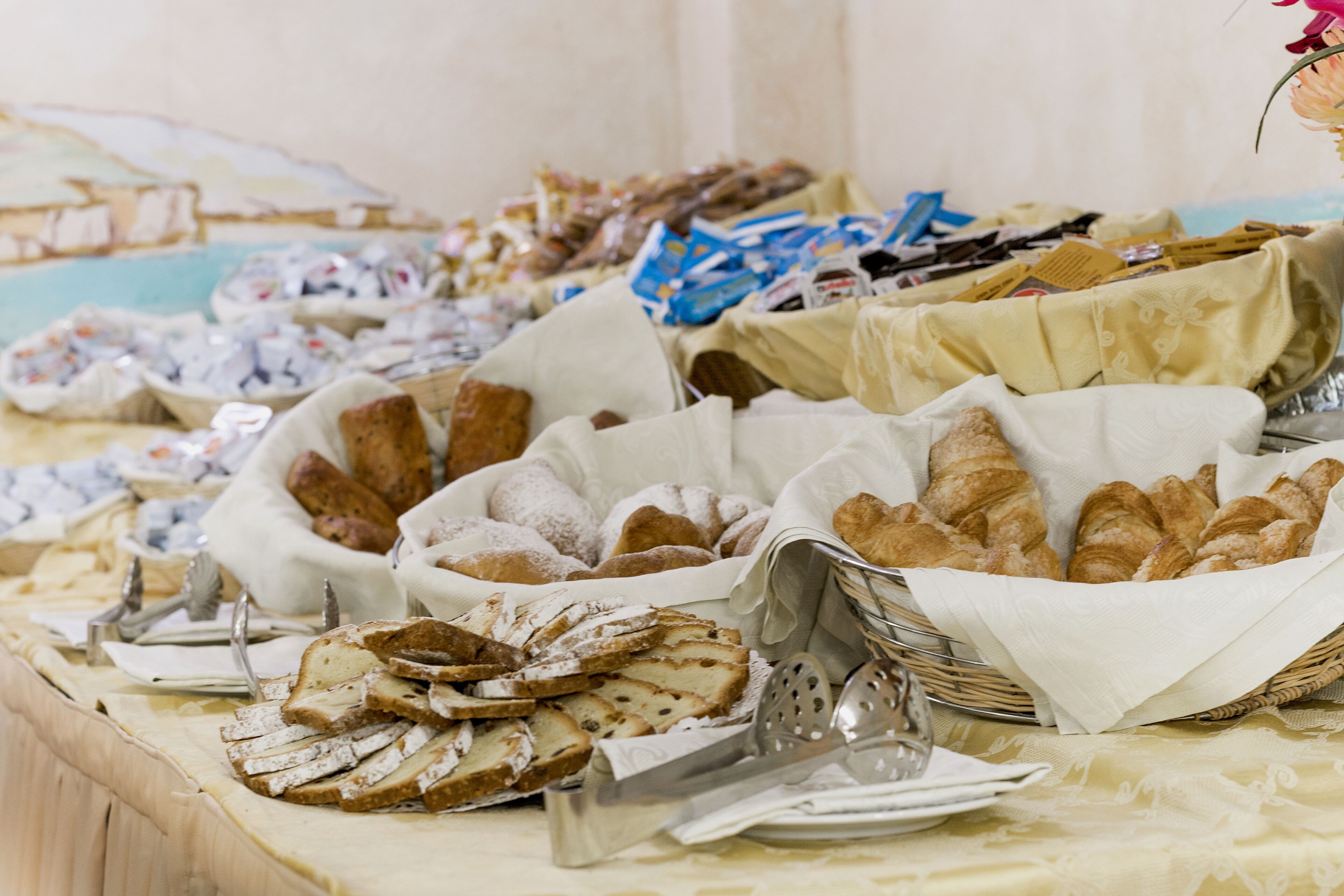 Una mesa de buffet con panes y pasteles varios.