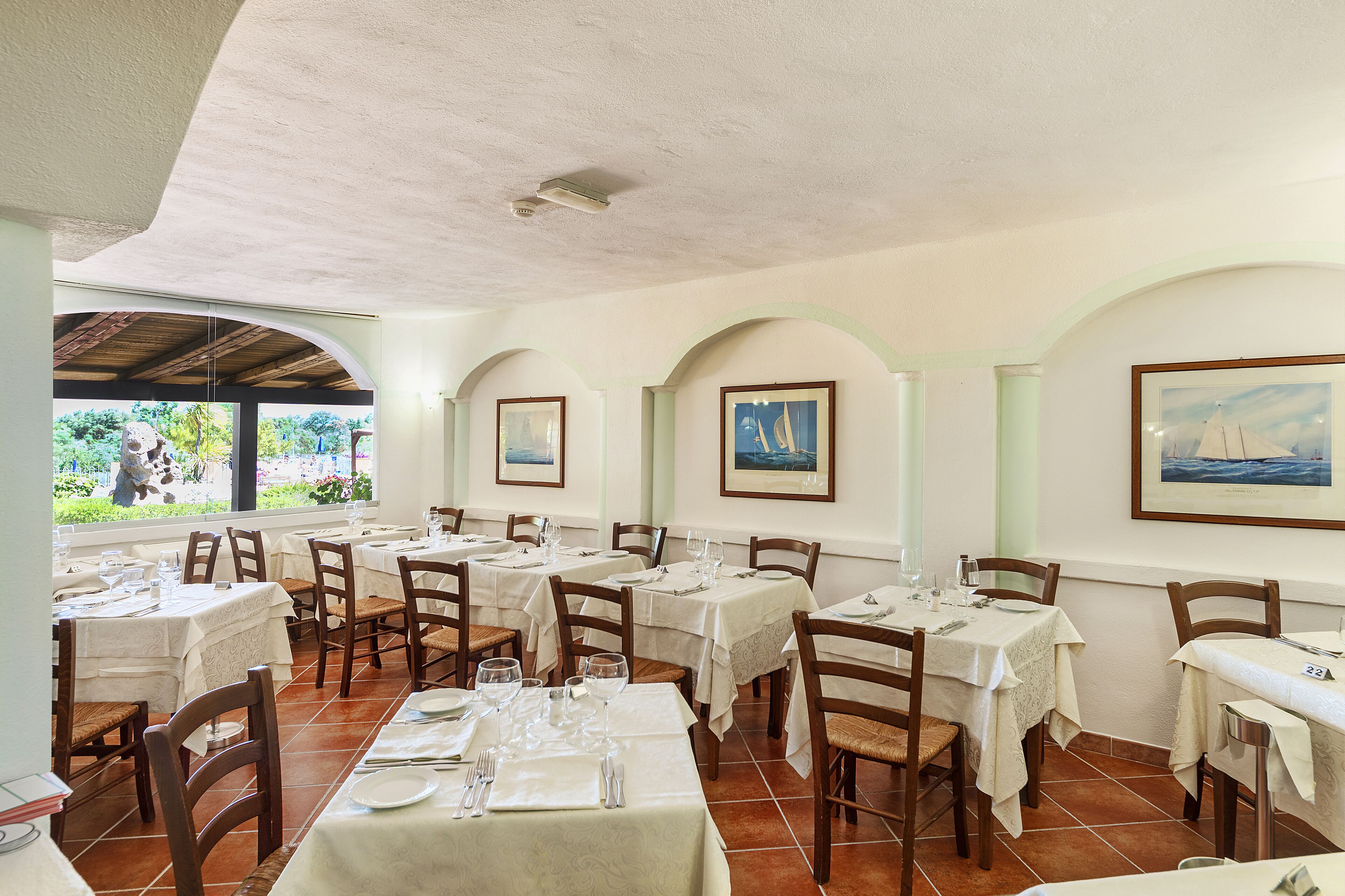 Un restaurant doté de nombreuses tables et chaises, chacune étant recouverte d’une nappe blanche et agrémentée de couverts en argent.