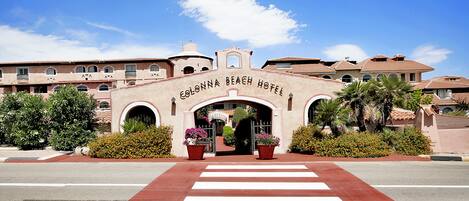 La entrada al Hotel Conna Beach, con un paso de peatones visible y un arco de bienvenida.