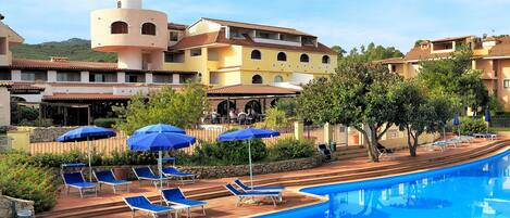 A resort with a swimming pool, sun loungers, and umbrellas.