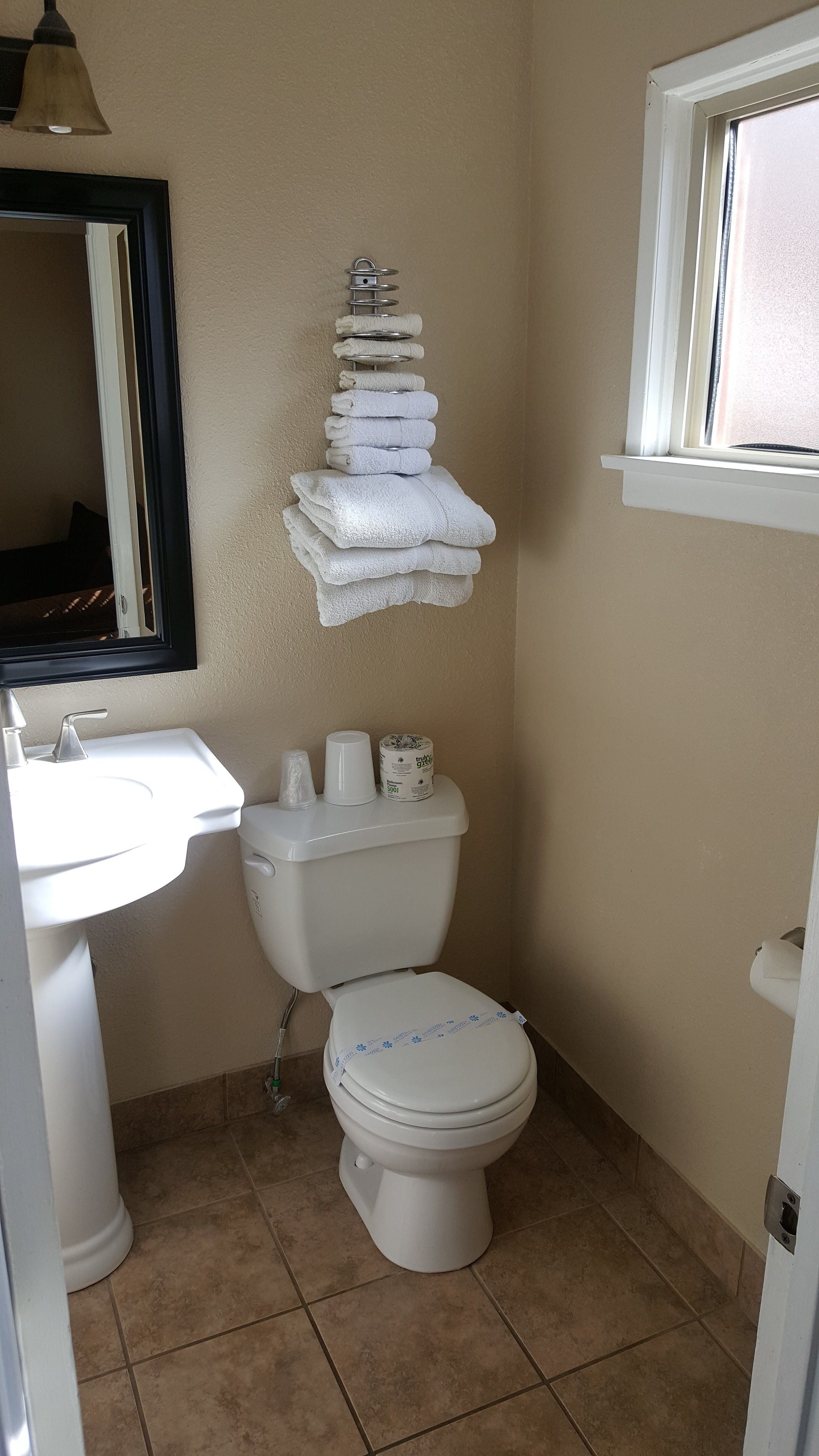 Ein Badezimmer mit Toilette, Waschbecken und einem Handtuchhalter mit Handtüchern.