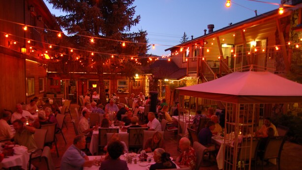 An outdoor dining area with string lights, tables, and chairs. - Robinhood Resort (Big Bear Lake)