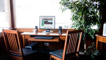 A wooden desk with a computer, two chairs, and a potted plant.