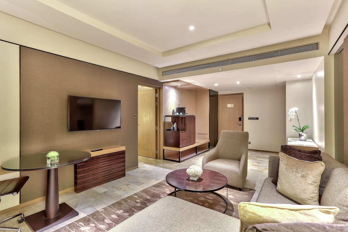 A modern living room with a flat-screen TV, a glass coffee table, a sofa, and a cabinet.