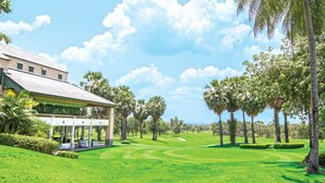 A golf course with a clubhouse, palm trees, and a clear sky. - Lake View Resort & Golf Club (Cha-am)