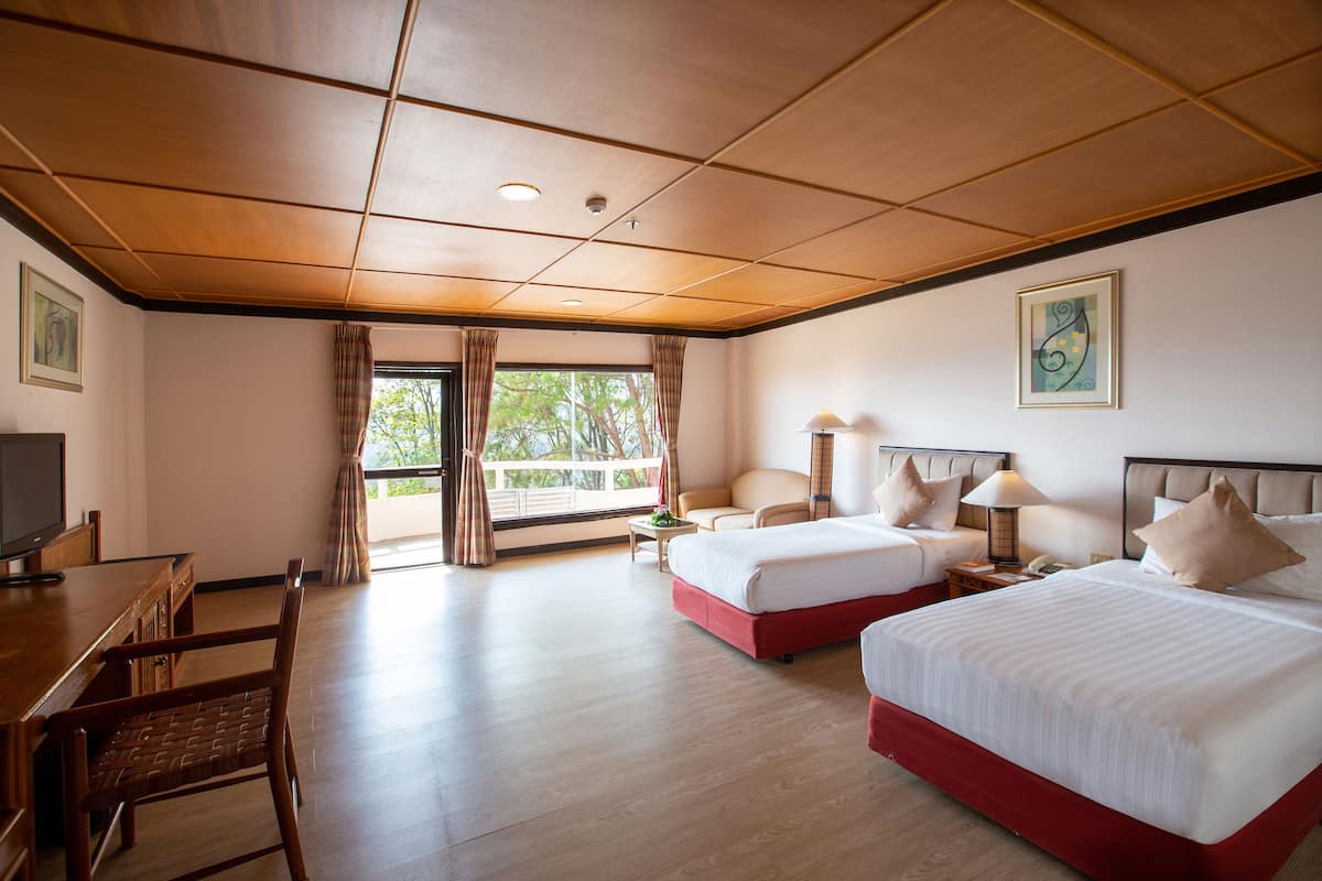 A hotel room with two beds, a desk, and a chair.