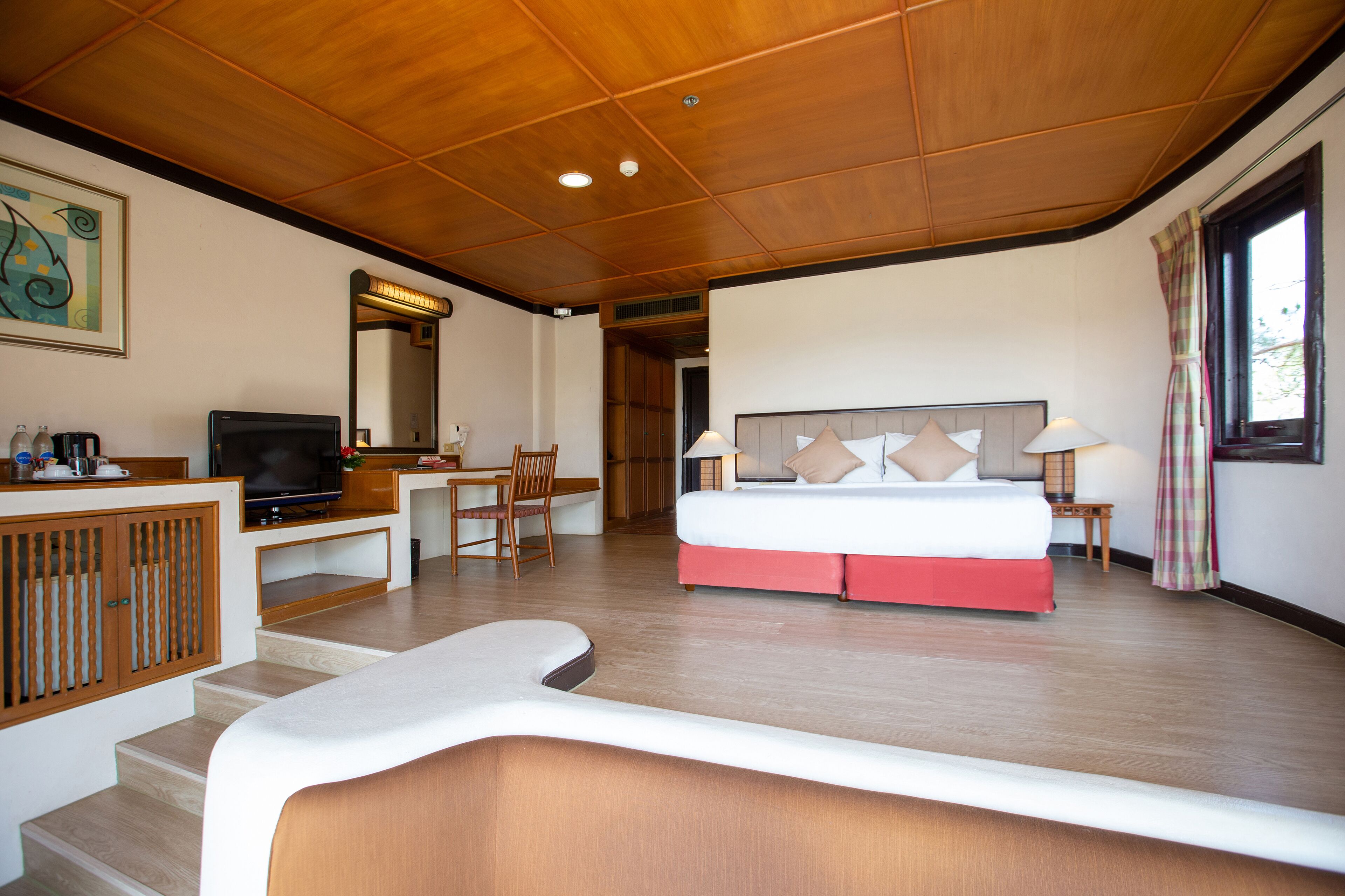 Una habitación de hotel con cama, escritorio, televisión y vistas al exterior.