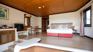A hotel room with a bed, desk, television, and a view of the outdoors.