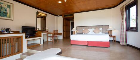 A hotel room with a bed, desk, television, and a view of the outdoors.