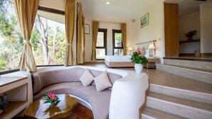 Ein modernes Wohnzimmer mit einer gebogenen Couch, einem Holztisch und Blick ins Freie durch große Fenster.