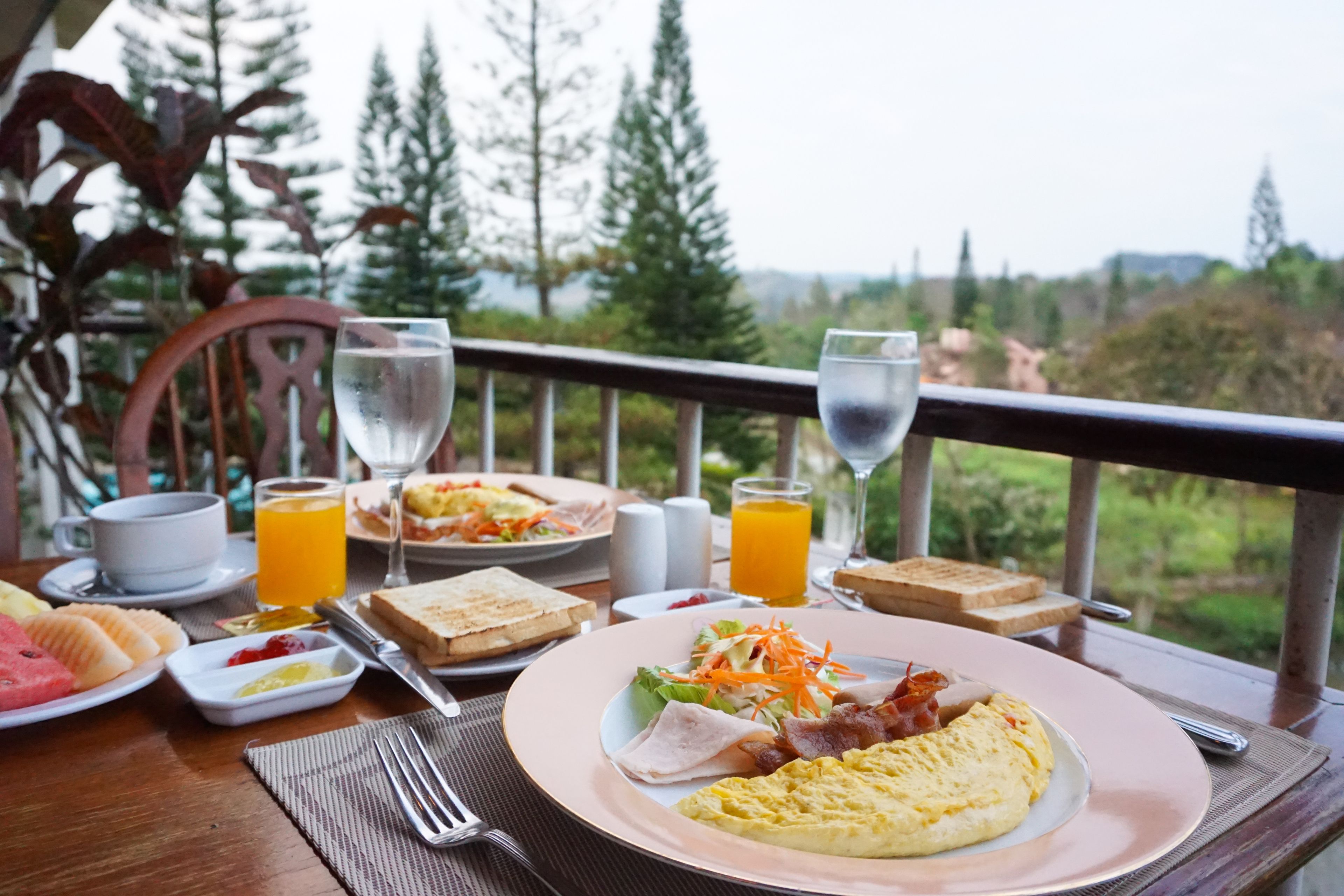 Una mesa de desayuno con platos de comida, vasos de zumo de naranja y una vista panorámica.