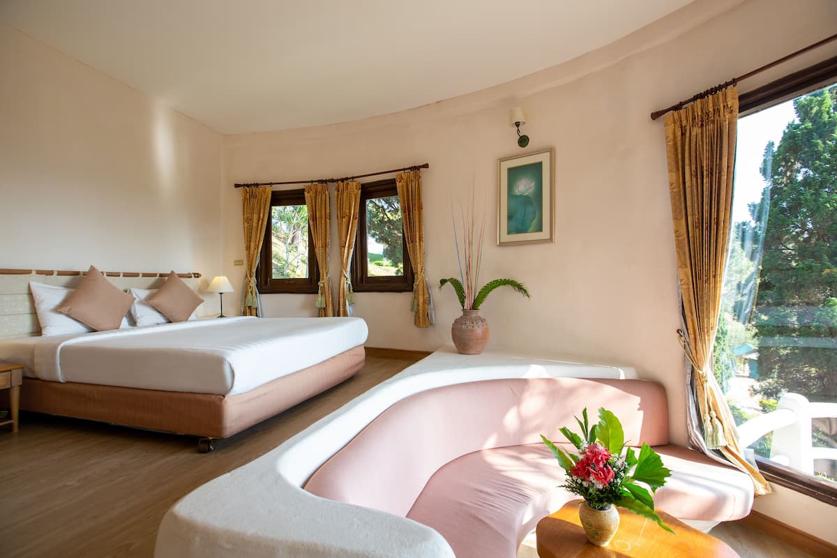 A bedroom with a bed, bedside table, and a window with curtains.