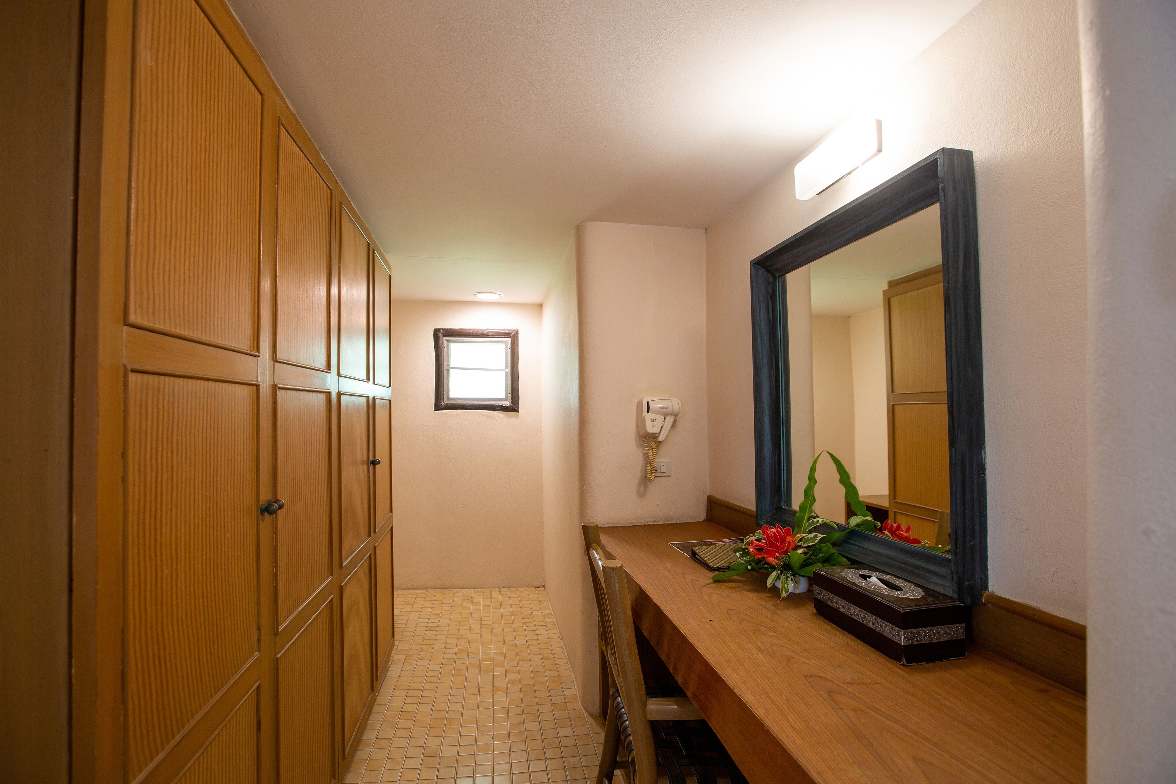 A hallway with wooden lockers, a mirror, a telephone, and a small window.