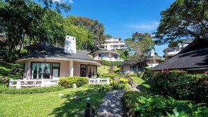 Ein Resort mit mehreren bungalowartigen Gebäuden, einem zentralen Weg und üppiger Vegetation.