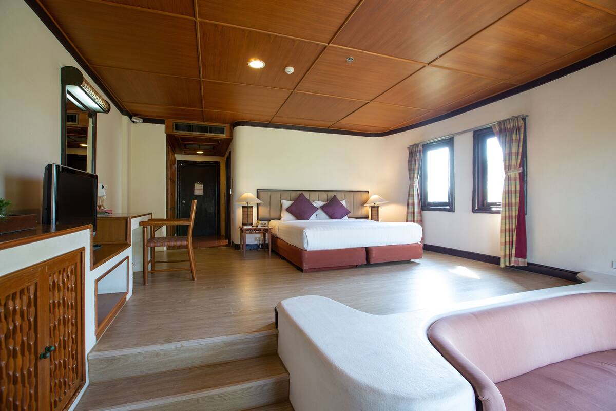 A hotel room with a bed, bedside tables, a TV, and a seating area.