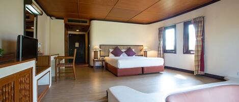 A hotel room with a bed, bedside tables, a TV, and a seating area.