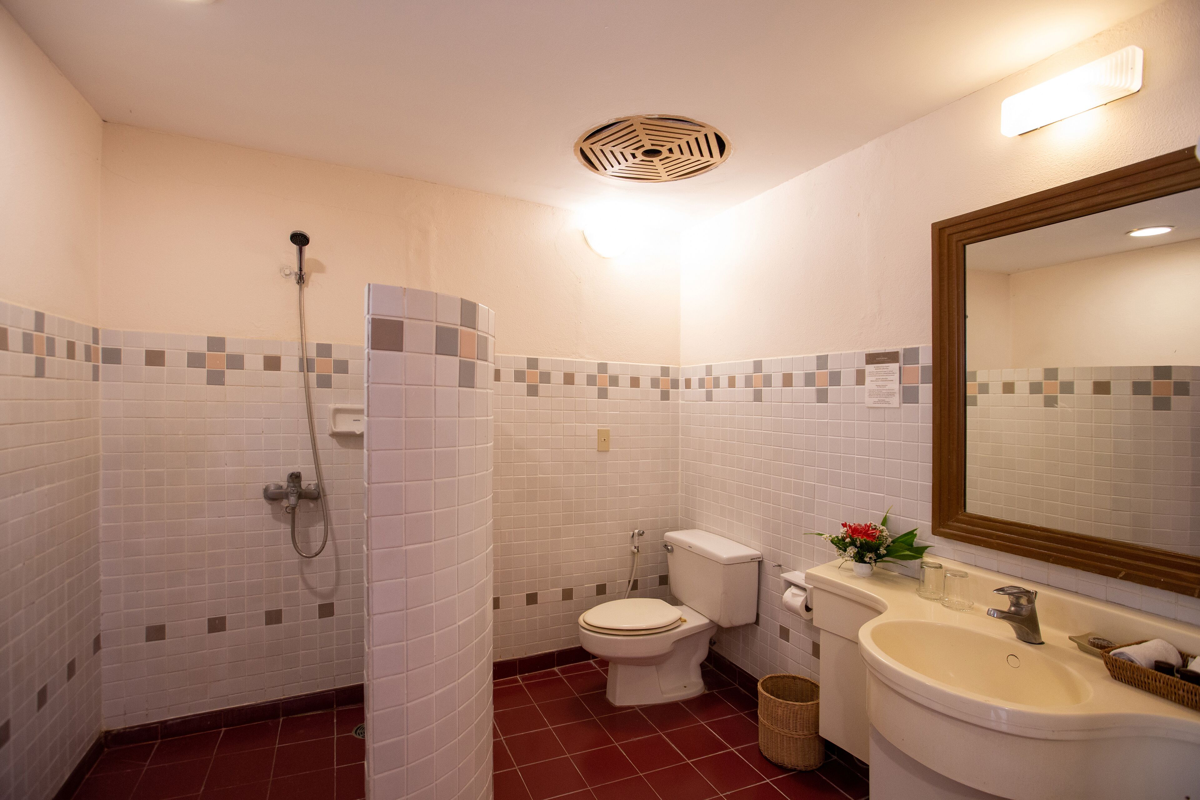 A bathroom with a shower, toilet, sink, and mirror.