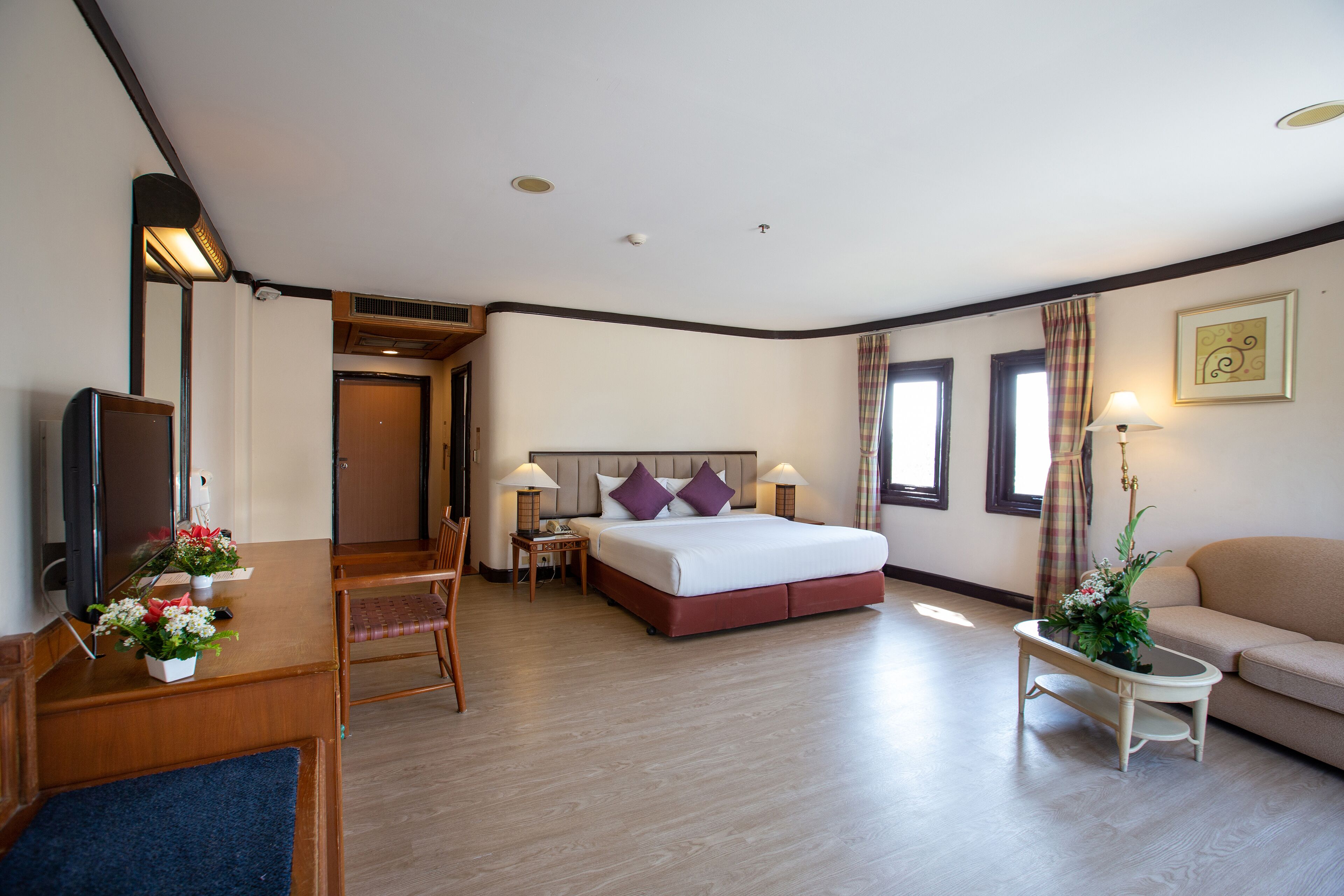 Una habitación de hotel con cama, escritorio, silla, sofá y televisor.
