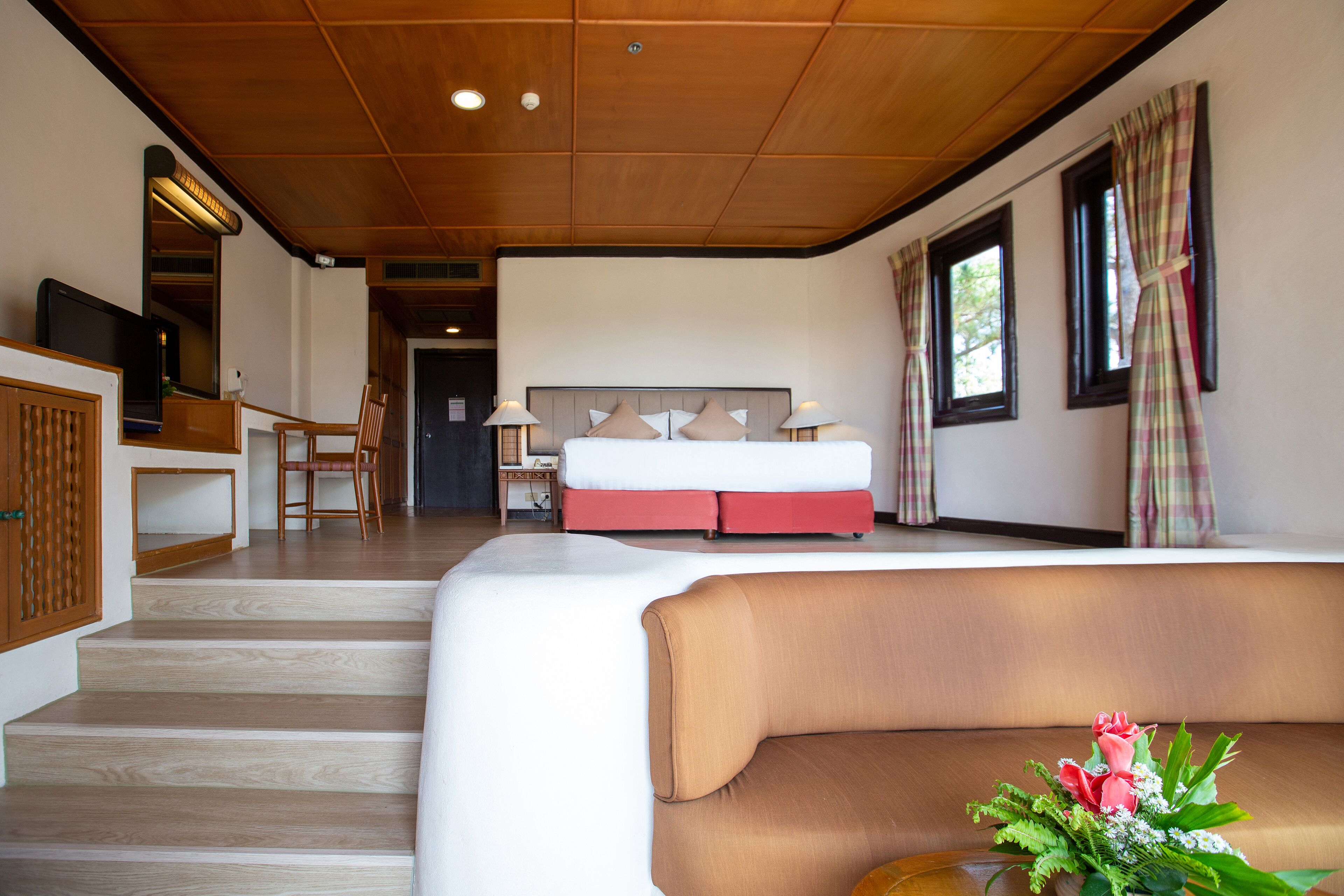 Una habitación de hotel con cama, sofá, televisión y escritorio.