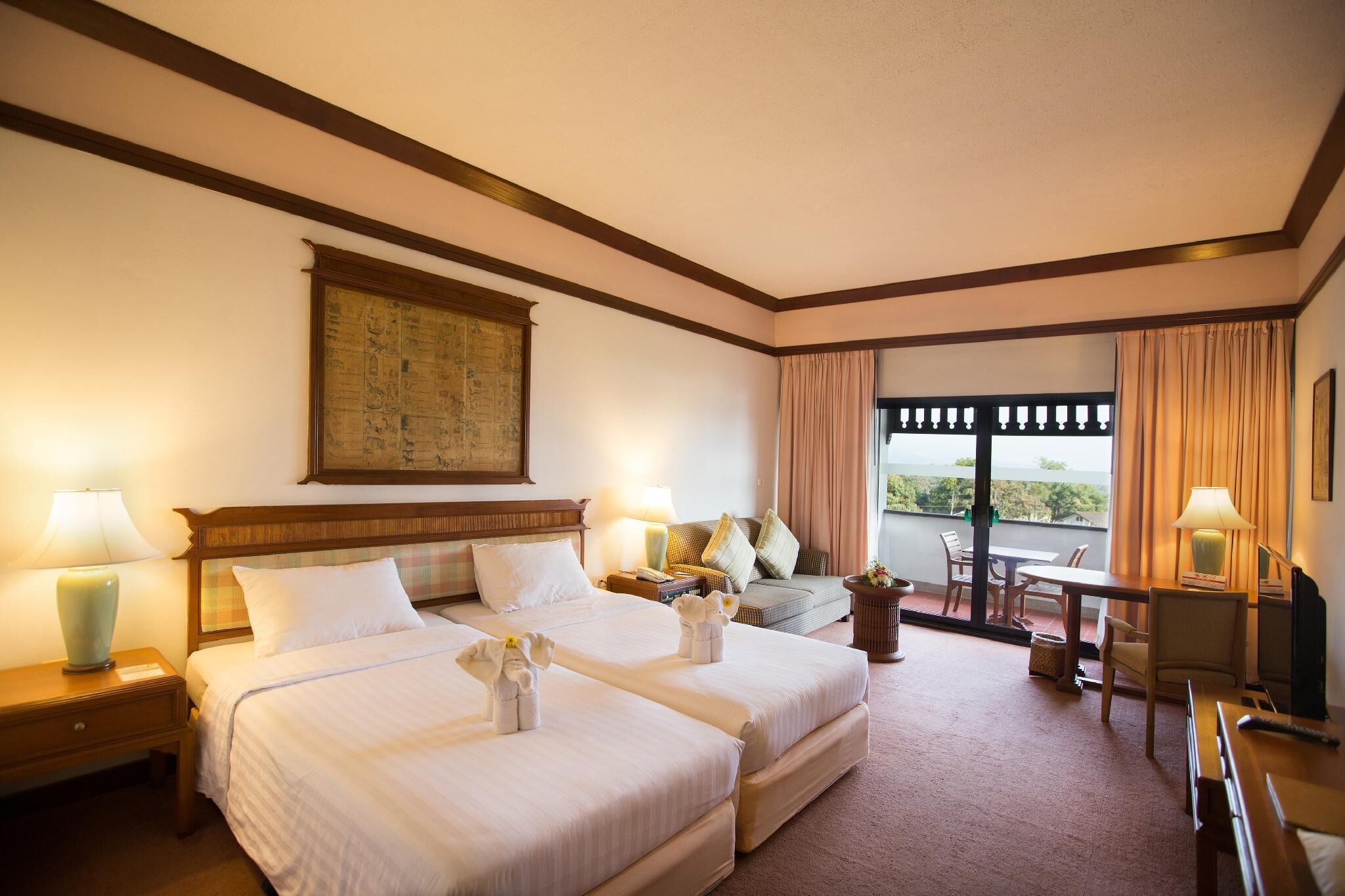 Habitación de hotel con dos camas, un balcón, zona de comedor y televisión.
