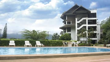 Una piscina al aire libre, sillones reclinables de piscina