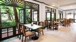 A spacious restaurant with multiple tables and chairs, large windows with a view of greenery, and a modern interior design. - The Imperial Chiang Mai Resort & Sports Club (Mae Rim)