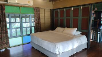 Un dormitorio con una cama grande, un equipo de aire acondicionado, una ventana con cortinas y piso de madera.