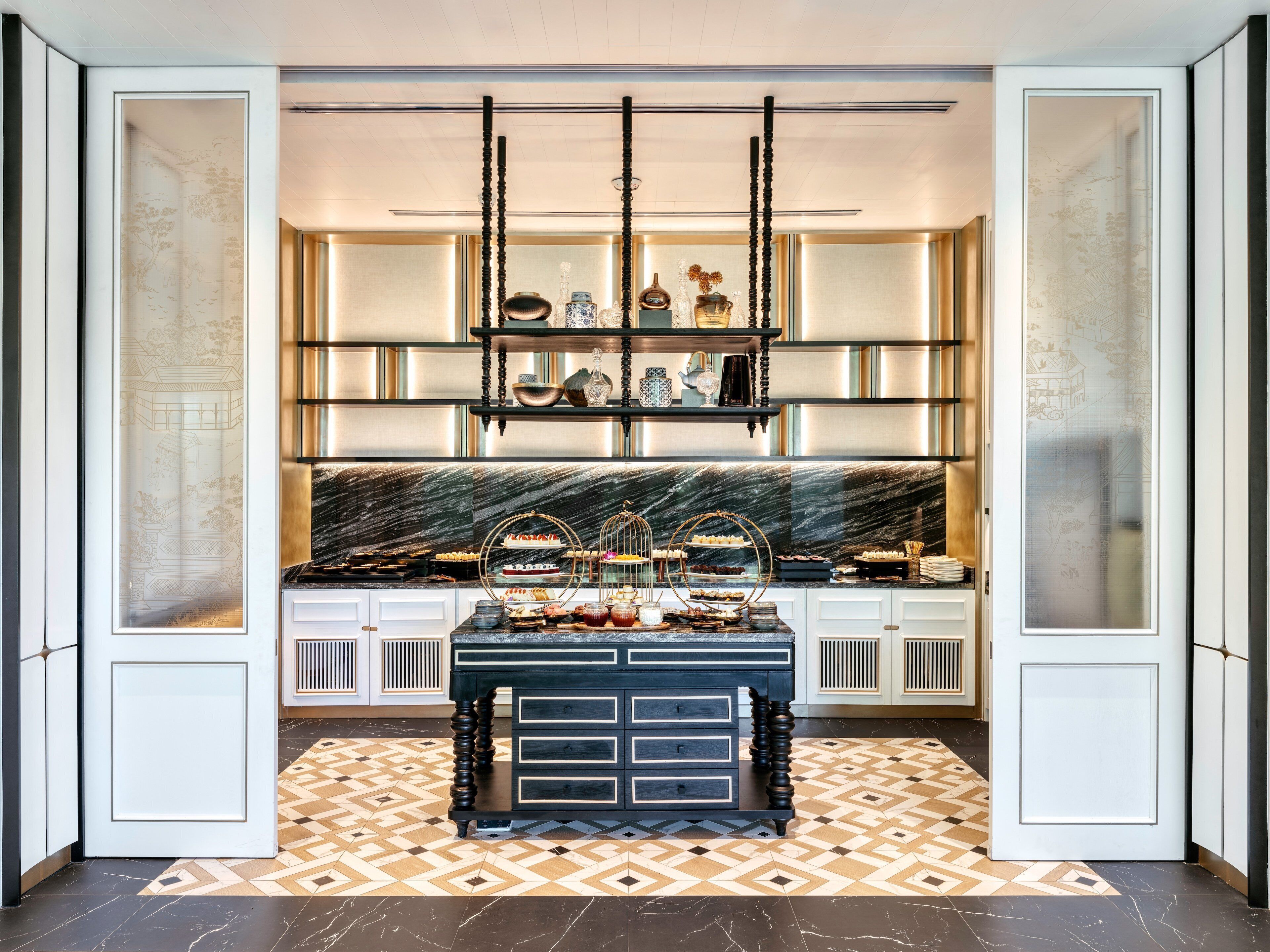 A modern kitchen with a marble countertop, black cabinets, and a decorative display shelf.
